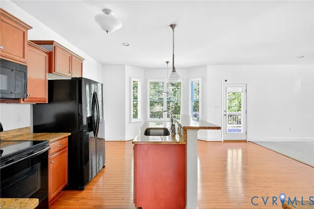 a kitchen with stainless steel appliances granite countertop a refrigerator a oven and a stove with wooden floor