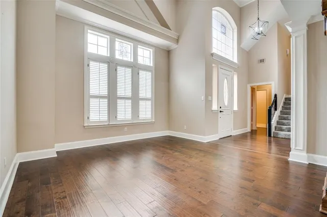 a view of an empty room with window and wooden floor