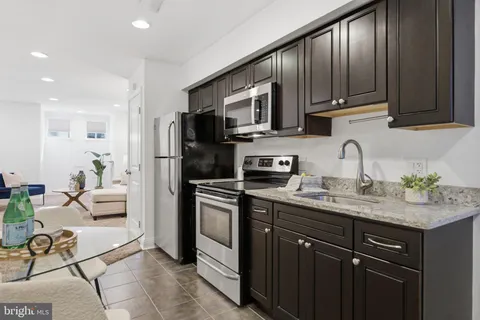 a kitchen with stainless steel appliances granite countertop a sink stove refrigerator and cabinets
