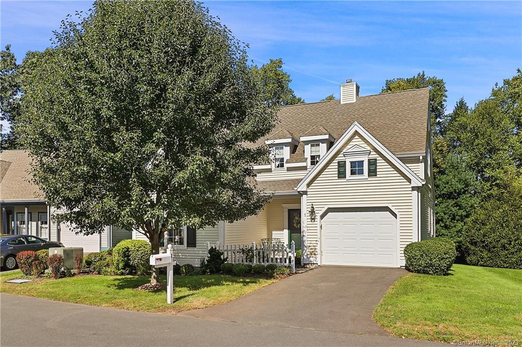 a view of a white house with a small yard and large tree