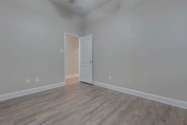 an empty room with wooden floor chandelier fan and windows