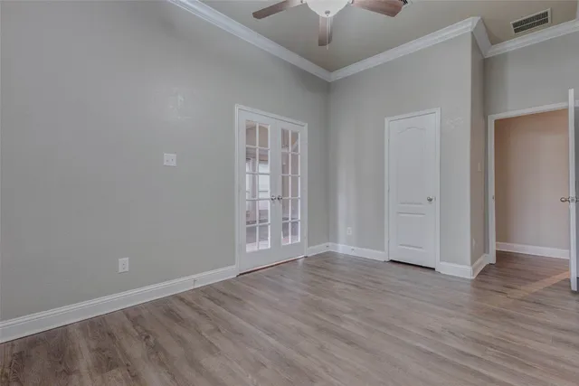 an empty room with wooden floor chandelier fan and windows