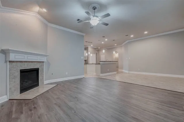 a view of an empty room with wooden floor and a fireplace