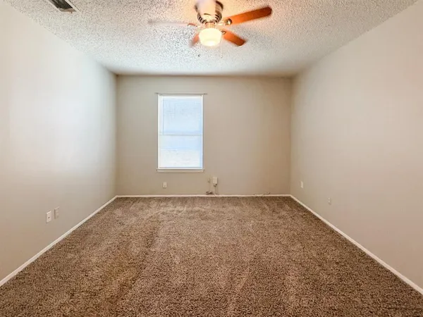 an empty room with a window and a fan