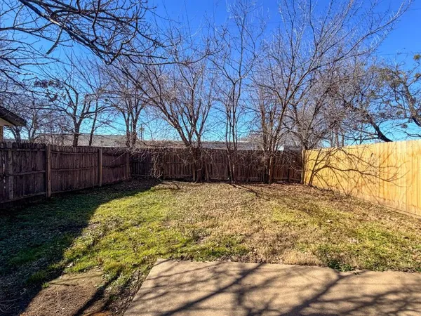 a view of backyard with wooden fence and large trees