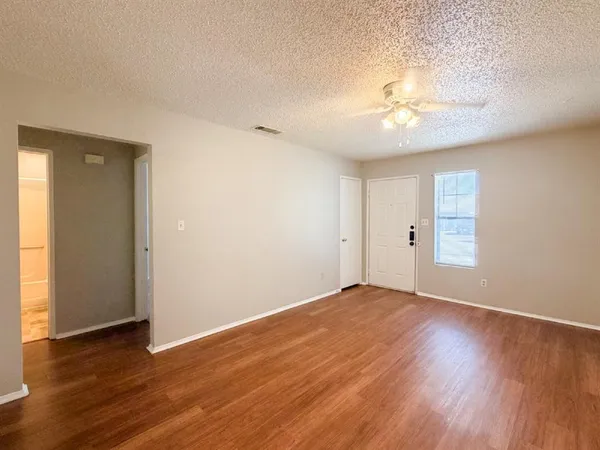 an empty room with wooden floor and windows