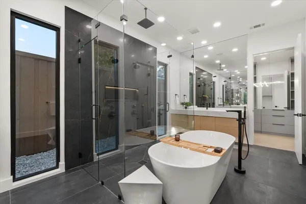 a bathroom with a tub shower sink mirror and a sink