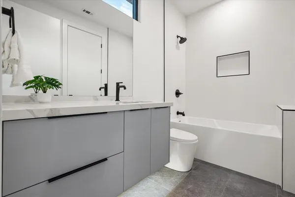 a bathroom with a granite countertop sink a toilet and a bathtub