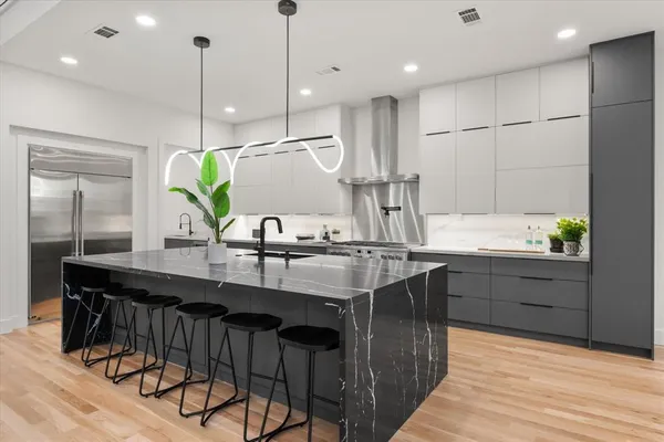 a kitchen with kitchen island granite countertop a sink a counter and chairs in it