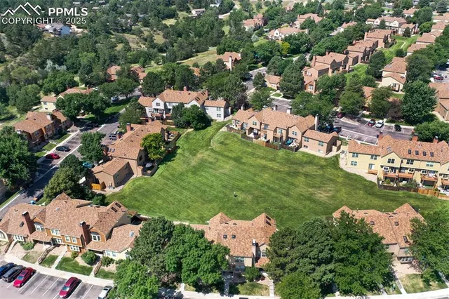 an aerial view of residential houses with outdoor space and trees