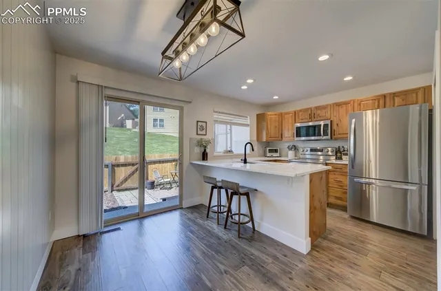 a kitchen with stainless steel appliances granite countertop a refrigerator a stove top oven a sink dishwasher and white cabinets with wooden floor