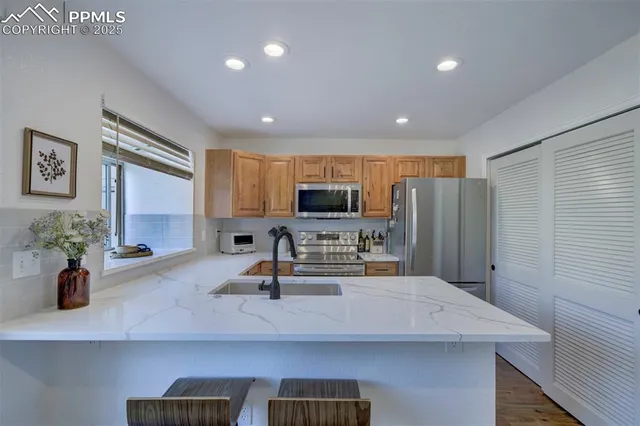 a kitchen with sink a refrigerator and chairs