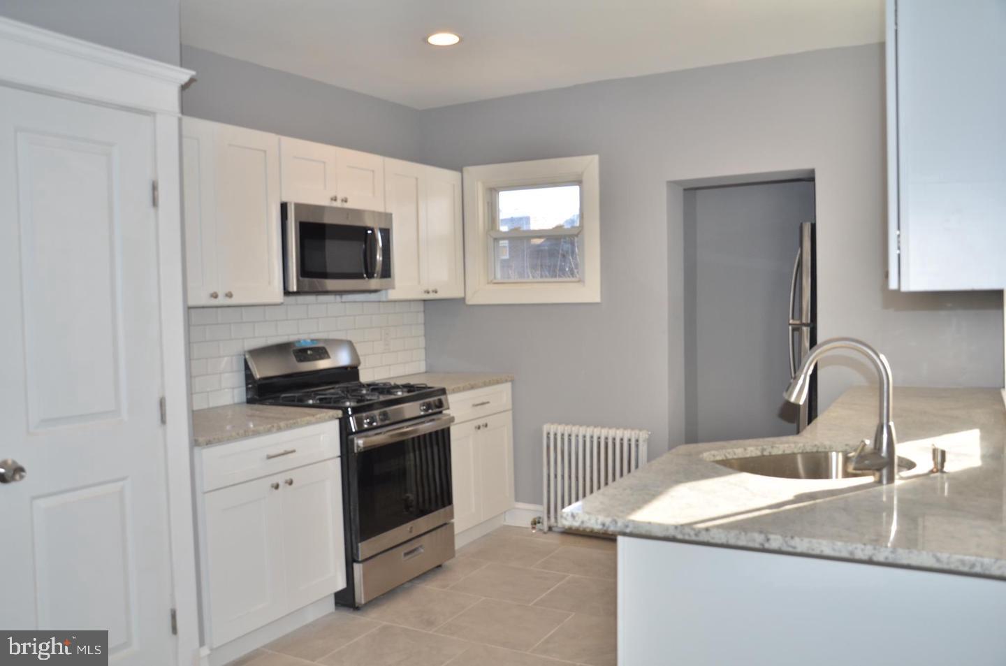 1758 South Avondale Street Philadelphia, PA 19142 - Photo 3 of 10 a kitchen with granite countertop a sink stainless steel appliances and white cabinets