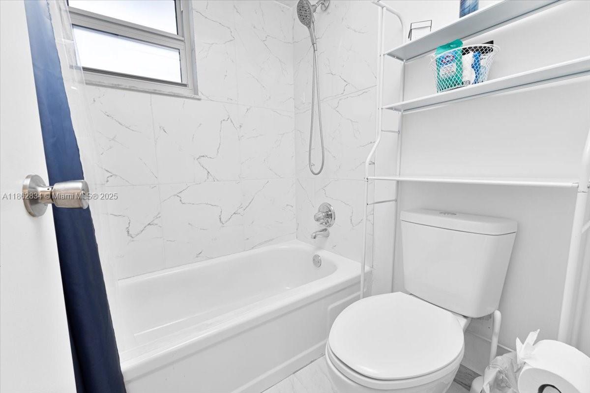 1501 South Ocean Boulevard, Unit 227 Lauderdale-by-the-Sea, FL 33062 - Photo 20 of 23 a white toilet and tub sitting next to a window