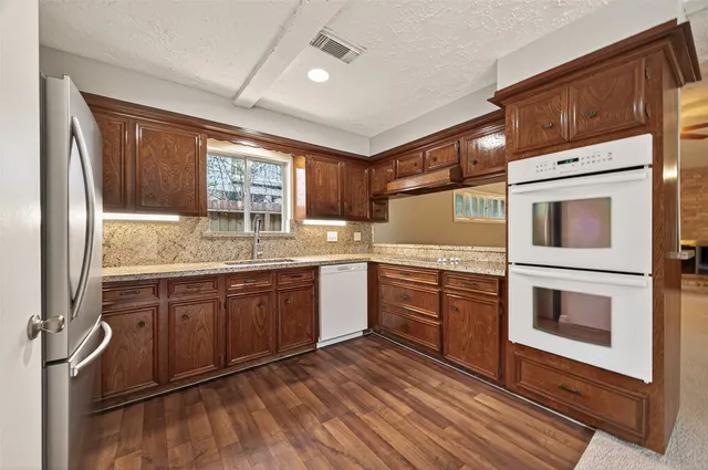 a kitchen with granite countertop stainless steel appliances sink stove and cabinets