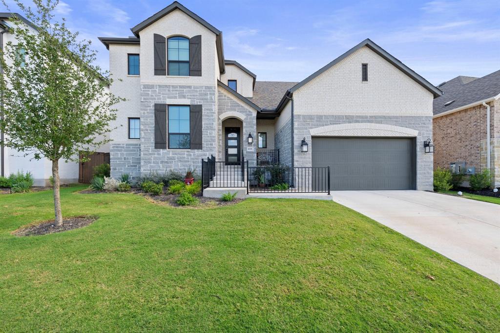 French provincial home with stone siding, driveway, a garage, and brick siding