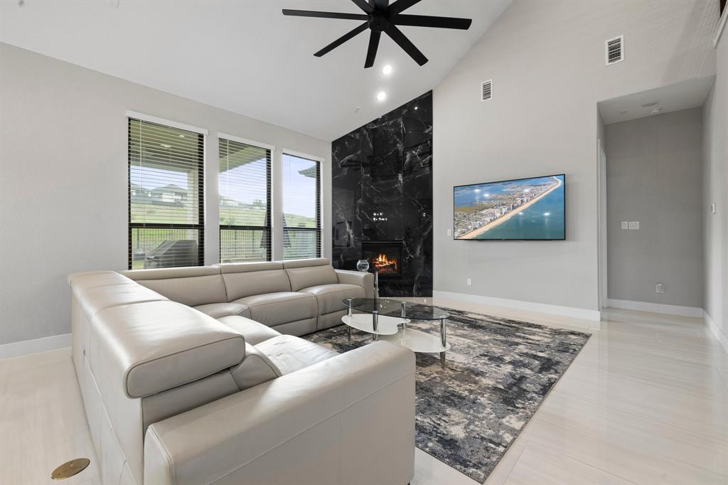 1008 Willie Rnch Way Leander, TX 78641 - Photo 13 of 40 Living area featuring a ceiling fan, vaulted ceiling, a high end fireplace, recessed lighting, and an accent wall