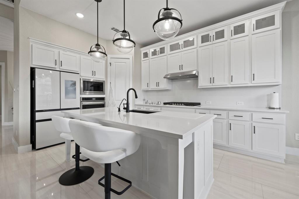 1008 Willie Rnch Way Leander, TX 78641 - Photo 15 of 40 Kitchen featuring stainless steel appliances, a breakfast bar area, white cabinets, a kitchen island with sink, and hanging light fixtures