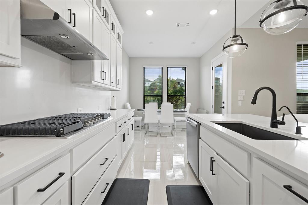 1008 Willie Rnch Way Leander, TX 78641 - Photo 16 of 40 Kitchen featuring white cabinets, light stone counters, stainless steel appliances, decorative light fixtures, and light tile patterned floors
