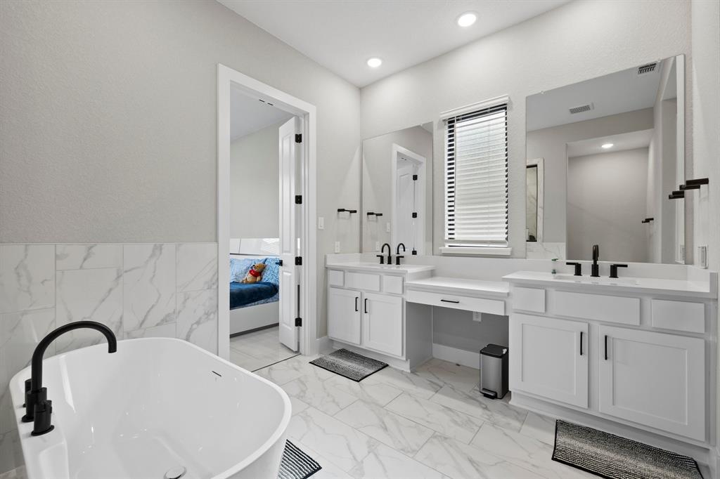 1008 Willie Rnch Way Leander, TX 78641 - Photo 21 of 40 Full bath with double vanity, a freestanding bath, light marble finish flooring, tile walls, and connected bathroom