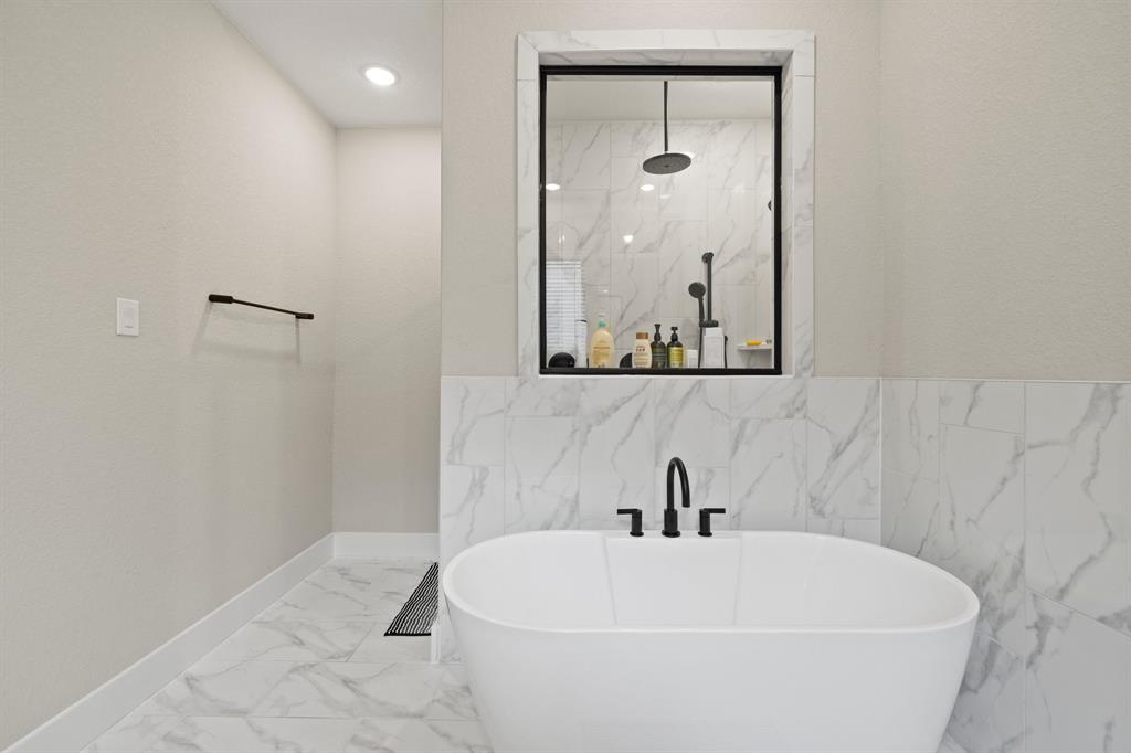 1008 Willie Rnch Way Leander, TX 78641 - Photo 22 of 40 Bathroom featuring marble look tiles, a soaking tub, a marble finish shower, and tile walls