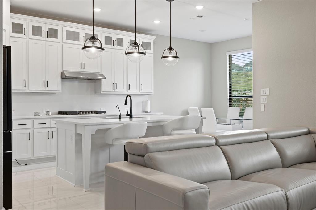 1008 Willie Rnch Way Leander, TX 78641 - Photo 39 of 40 Kitchen featuring open floor plan, white cabinets, a kitchen island with sink, decorative light fixtures, and glass insert cabinets