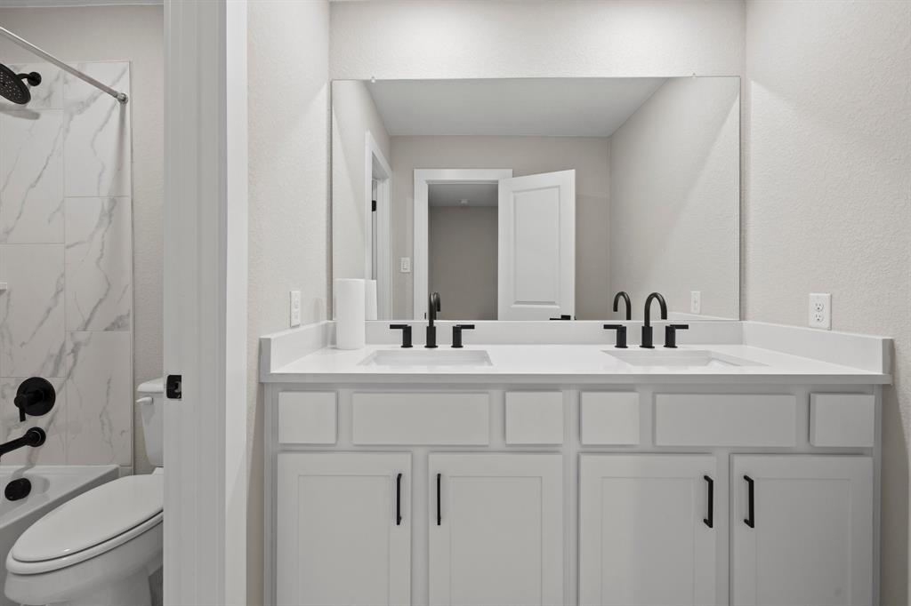 1008 Willie Rnch Way Leander, TX 78641 - Photo 25 of 40 Bathroom with double vanity, bathtub / shower combination, and a textured wall