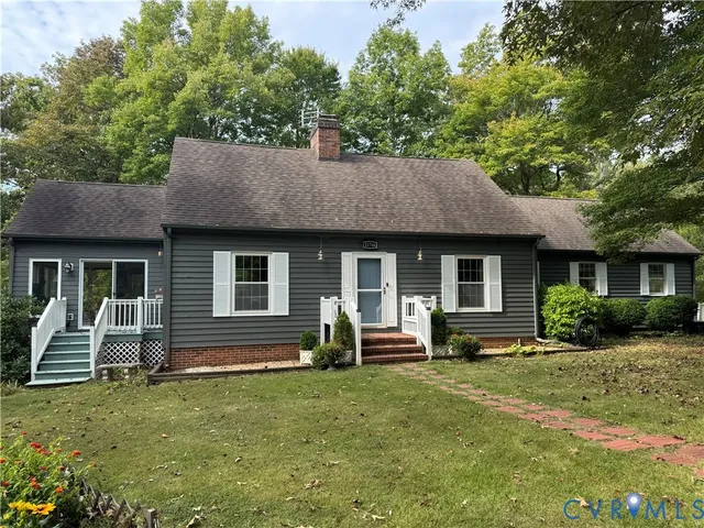 a front view of a house with a garden and chairs