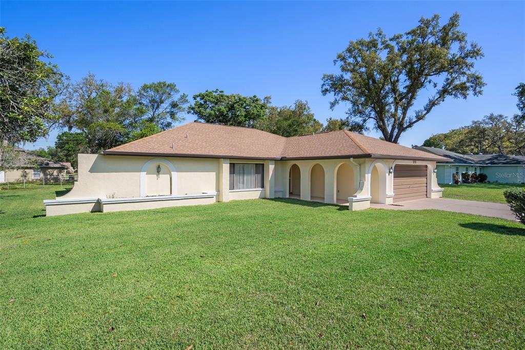 2131 Meadow Lark Road Spring Hill, FL 34608 - Photo 1 of 1 a white house with a big yard plants and large trees