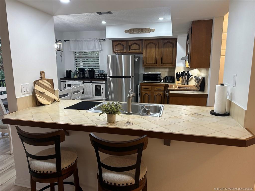 4095 Southeast Centerboard Lane, Unit 6B Stuart, FL 34997 - Photo 13 of 83 a kitchen with granite countertop kitchen island stainless steel appliances a sink and a refrigerator