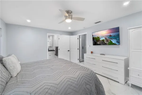 a spacious bedroom with a bed and a flat screen tv