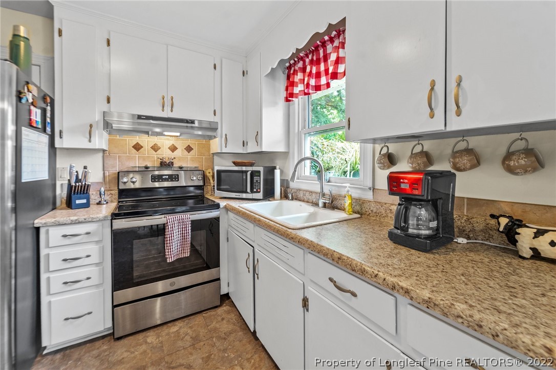 1103 Vass Road Spring Lake, NC 28390 - Photo 16 of 37 a kitchen with stainless steel appliances granite countertop a sink a stove and a wooden floor