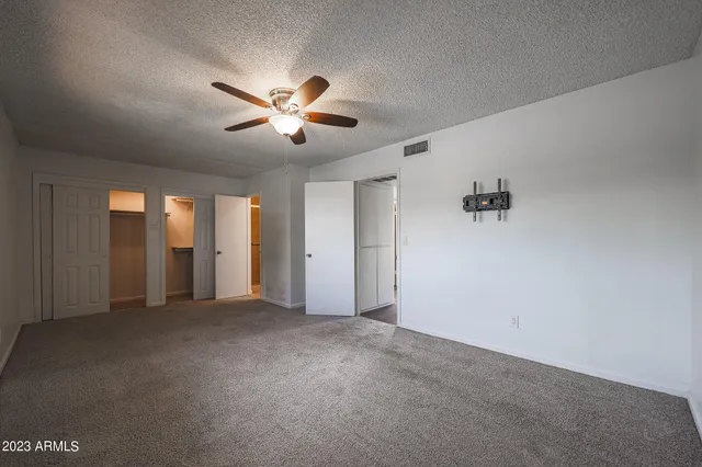 a view of an empty room with chandelier fan and window