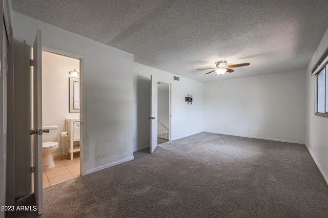a view of an empty room with a chandelier fan and a window