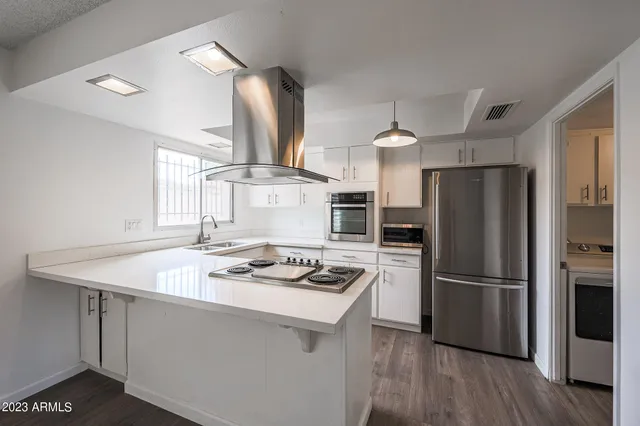 a kitchen with kitchen island a counter space a sink appliances and cabinets