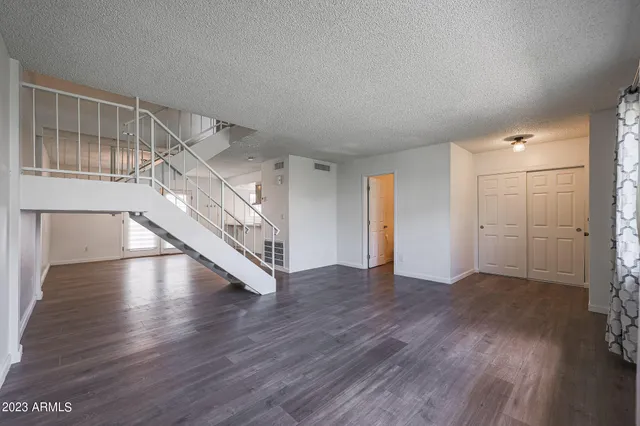 a view of an empty room with wooden floor and stairs
