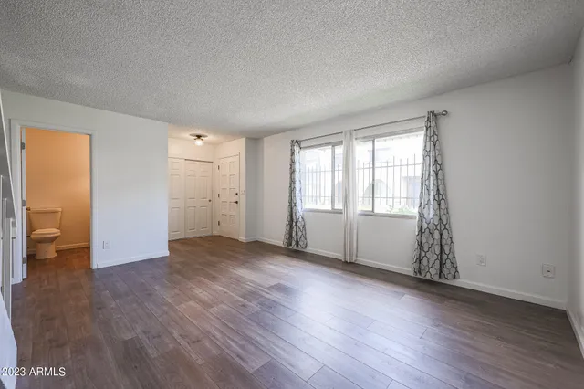 an empty room with wooden floor and windows