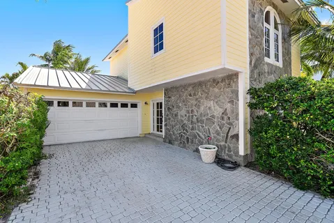 a view of a big house with potted plants and a yard