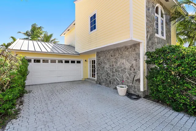 a view of a big house with potted plants and a yard