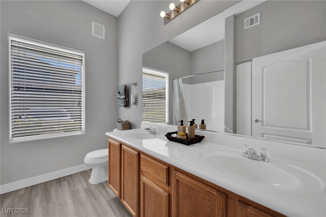 3544 Desert Cliff Street, Unit 101 Las Vegas, NV 89129 - Photo 18 of 29 Full bath featuring a shower with curtain, double vanity, and light wood-type flooring