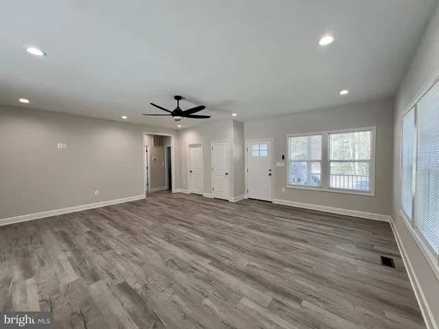 an empty room with wooden floor cabinet and windows