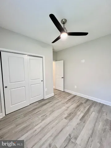 an empty room with wooden floor ceiling fan and windows