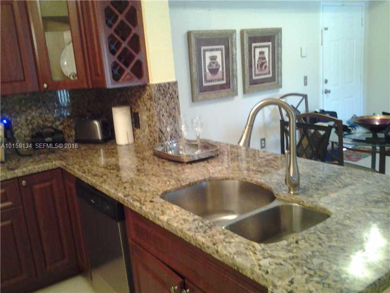 15480 Southwest 284th Street, Unit 2207 Homestead, FL 33033 - Photo 1 of 12 a kitchen with granite countertop a sink and a wooden cabinets