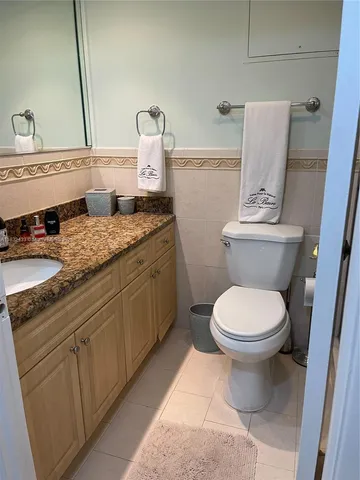 a bathroom with a granite countertop toilet sink and mirror