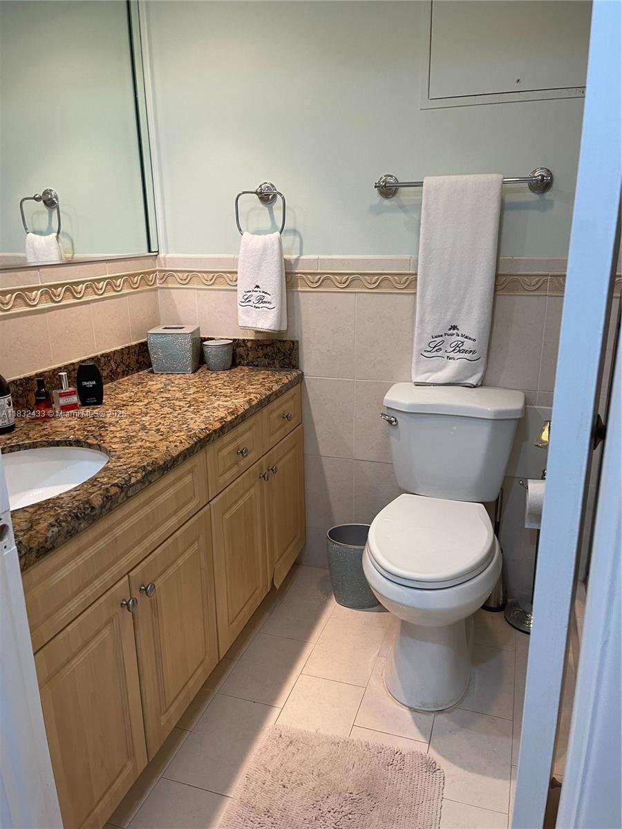 6039 Collins Avenue, Unit 823 Miami Beach, FL 33140 - Photo 13 of 21 a bathroom with a granite countertop toilet sink and mirror
