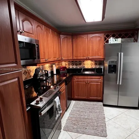 a kitchen with granite countertop a stove a sink and a refrigerator