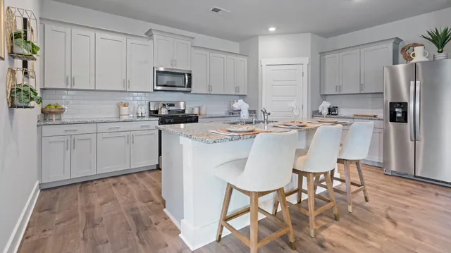 a kitchen with stainless steel appliances a dining table chairs microwave and sink