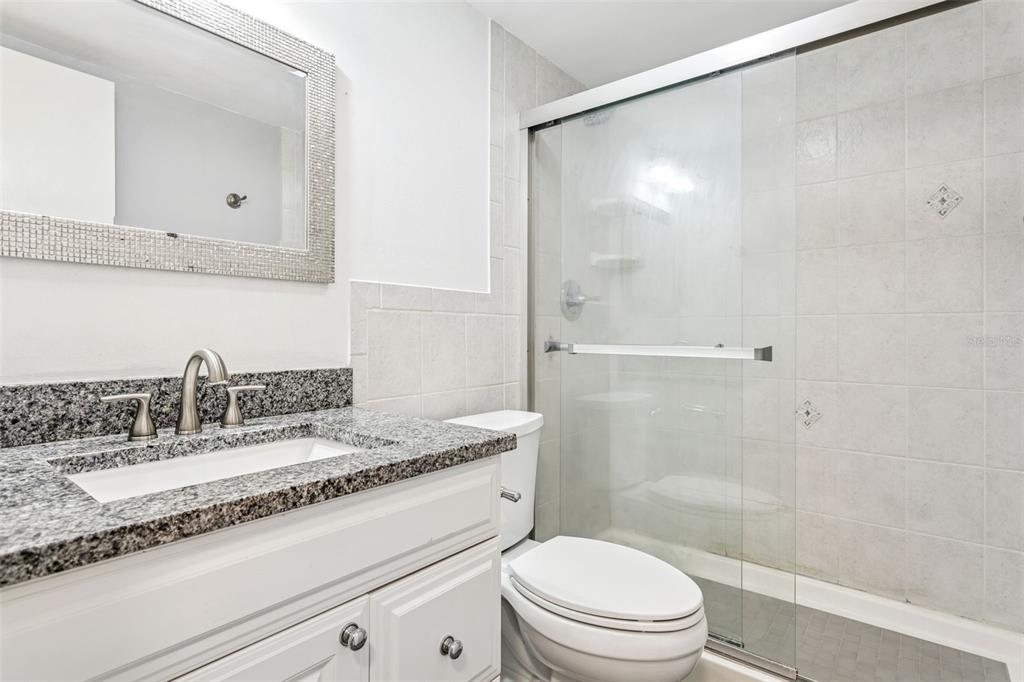 4606 West Gray Street, Unit 105 Tampa, FL 33609 - Photo 14 of 25 a bathroom with a granite countertop sink a toilet and shower