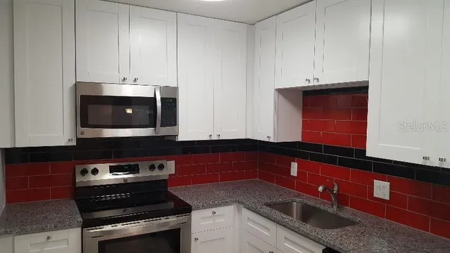a kitchen with granite countertop white cabinets and stainless steel appliances