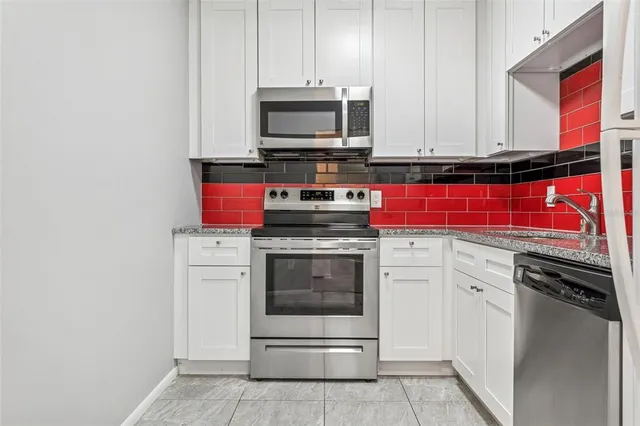 a kitchen with white cabinets and a refrigerator